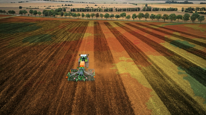 Un tractor Fendt verde con implemento trabajando el campo con precisión gracias al control de máquinas FendtONE.