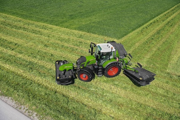 Fendt 600 Vario El tractor verde Fendt 600 Vario con llantas rojas y la segadora Fendt Slicer trabajando en un gran prado verde a vista de pájaro.