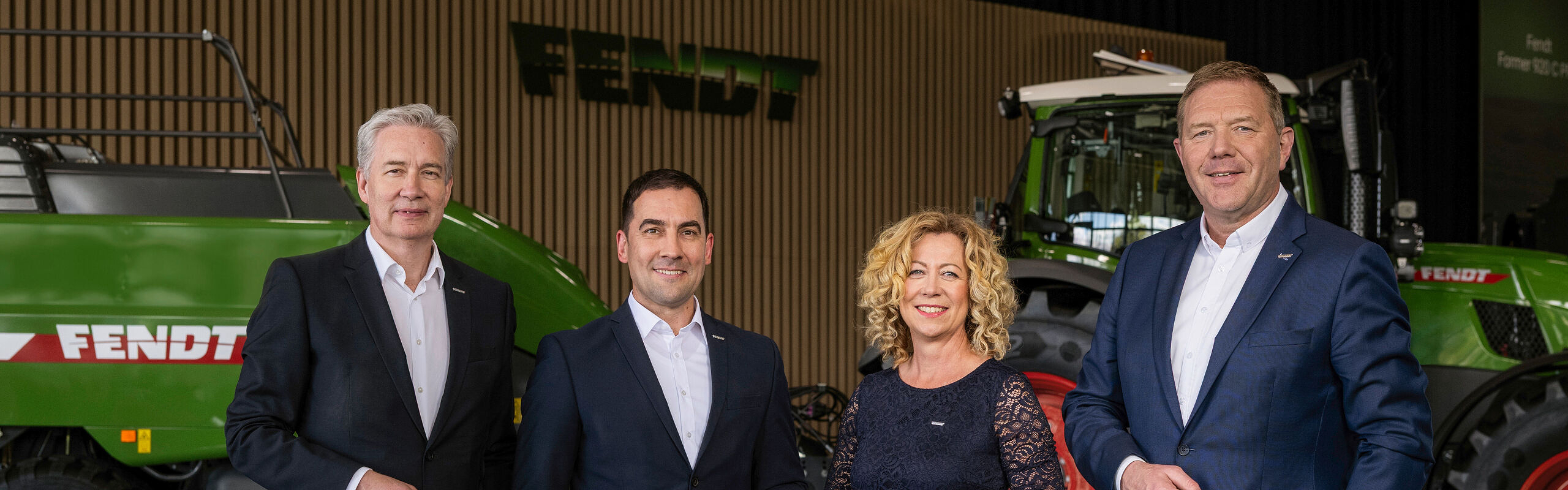 De izquierda a derecha, los gerentes Ekkehart Gläser, Dr. Josef Mayer, Ingrid Bußjäger-Martin y Christoph Gröblinghoff se encuentran en el Foro Fendt delante de un tractor Fendt y una empacadora rectangular Fendt.