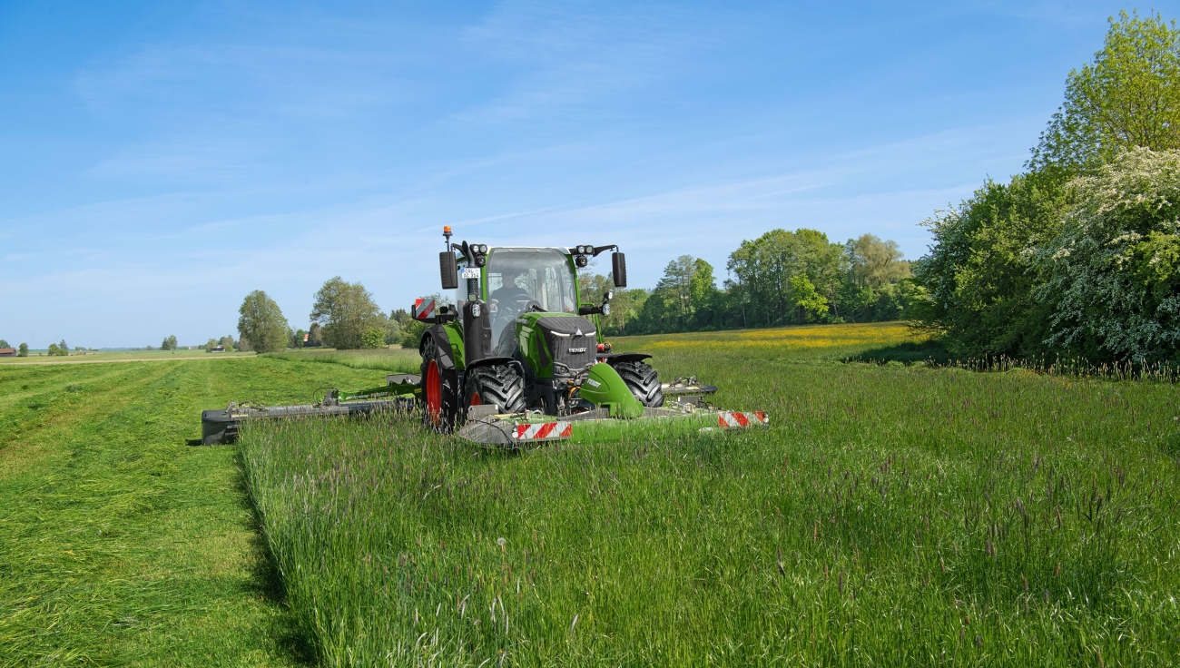 Fendt 300 Vario siega praderas con la combinación de segadoras Fendt Slicer. Un Fendt 300 Vario verde siega prados con una segadora frontal y trasera Fendt Slicer.
