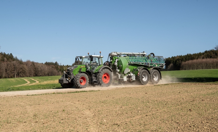 Fendt 724 Vario Gen7.1 con cisterna para purines Un Fendt 724 Vario Gen7.1 verde circula por una pista de tierra con un camión cisterna para purines.