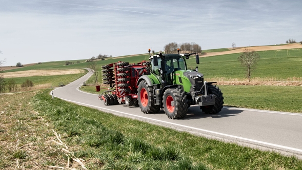 Un Fendt 700 Vario Gen7.1 con un remolque enganchado circula por una carretera comarcal de un paisaje de montaña.