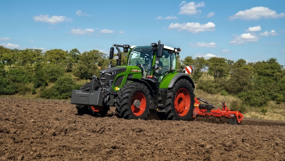 Fendt 600 Vario durante el trabajo del suelo en el campo Un Fendt 600 Vario trabaja en un campo recién cultivado, enmarcado por árboles
