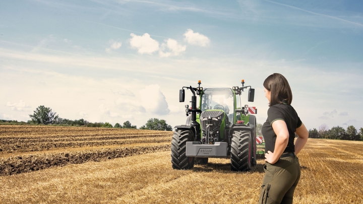 Una agricultora de pie en un rastrojo delante de su Fendt 700 Vario Gen7.