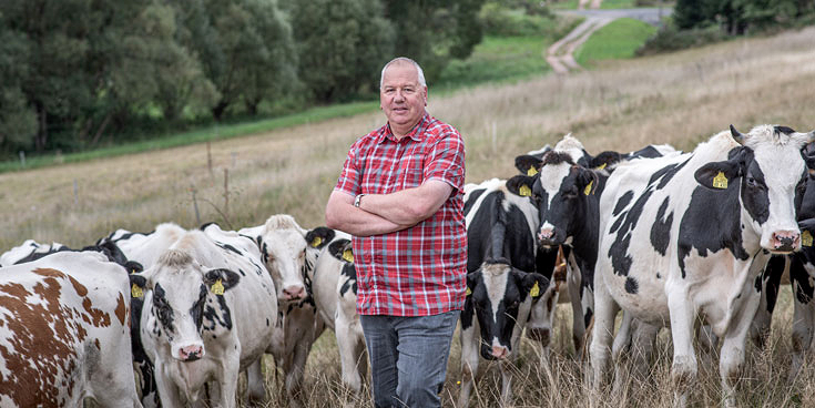 Maanviljelijä Silvio Reimann seisoo ylpeänä lehmälaumansa edessä