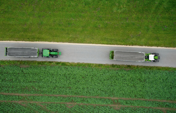 Fendt 728 Vario Gen7 Tigo-noukinvaunun kanssa peltojen välisellä tiellä ylhäältä katsottuna