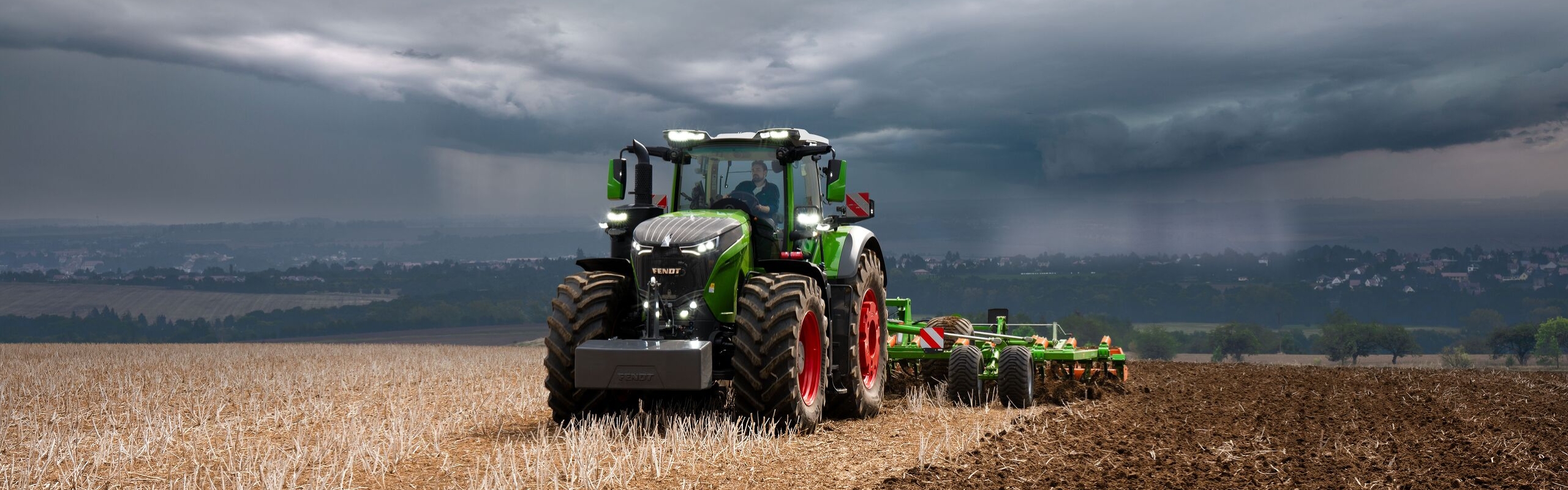 Kaukaisuudessa näkyvien raskaiden ukkospilvien edessä Fendt 1000 Vario -traktori työskentelee edelleen tehokkaasti pellolla