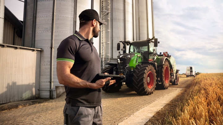 Fendtin huoltoteknikko katselee Fendt 700 Vario Gen6 -traktoria pellon reunassa.