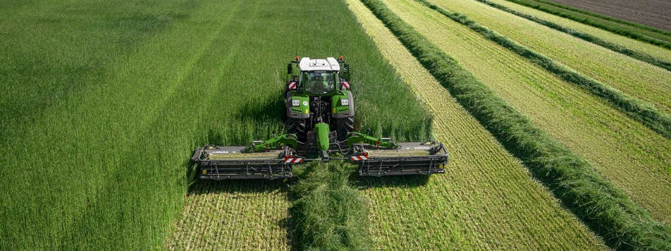 Fendt Slicer 960 KCB Pro Fendt-traktori ja Fendt Slicer 960 KCB Pro -niittokoneyhdistelmä leikkaavat niittyä lintuperspektiivistä.