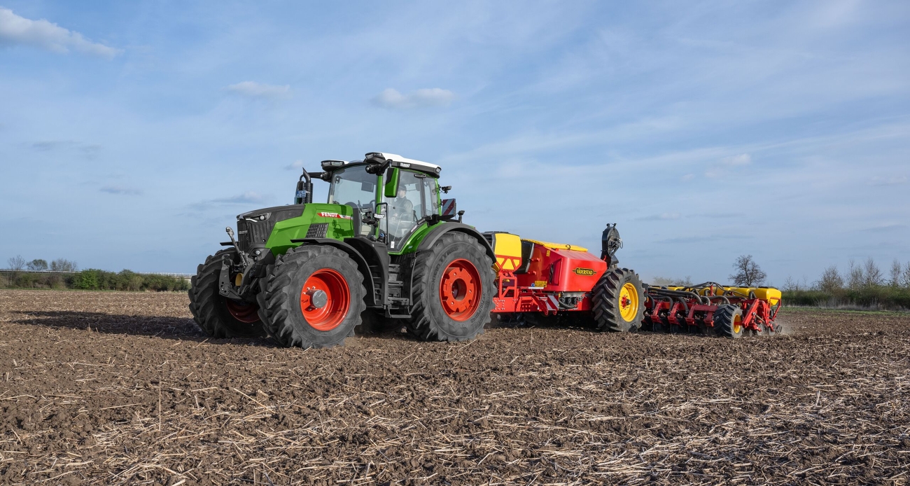 Fendt 800 Vario -traktorin suuri hydrauliteho kylvökoneen kanssa Vihreä Fendt 800 Vario työskentelee punaisen Väderstad-kylvökoneen kanssa pellolla.