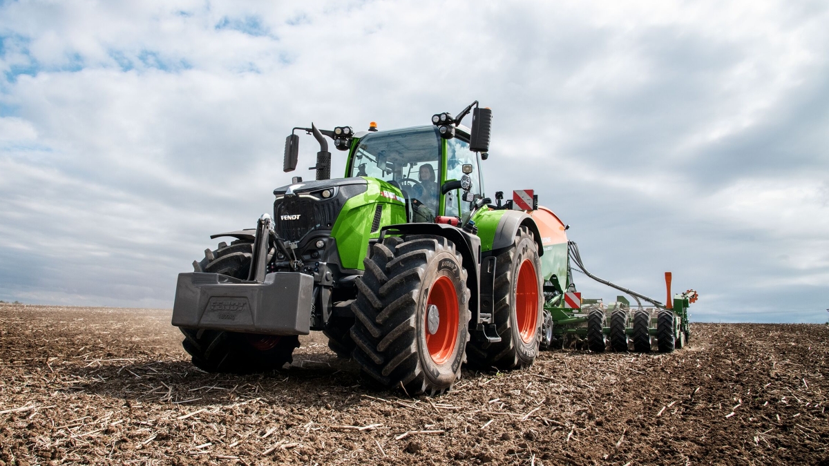 Maanviljelijä ajaa tiellä Fendt 700 Vario Gen7:llä pellolla
