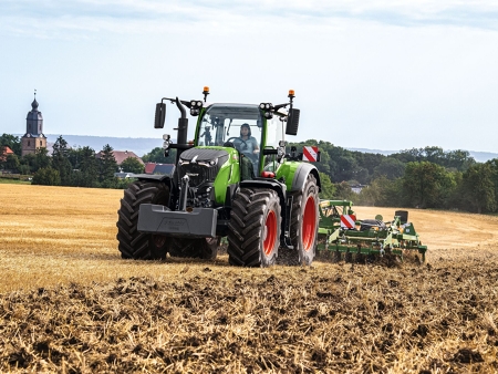 Maanviljelijä ajaa Fendt 700 Vario Gen7 -traktoria ja kultivaattoria pellolla.