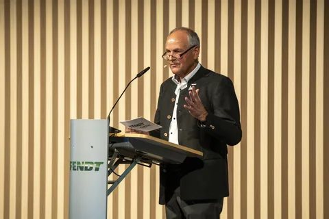 Sepp Nuscheler se tient devant un pupitre portant le logo Fendt et prononce un discours.
