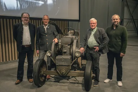 Une partie du comité directeur du Fendt Classic Club International, Karl-Heinz Welz, Sepp Nuscheler, Hans Heinle et Bernhard Bartussek, se tient dans le hall du Fendt Forum autour d'un ancien tracteur Fendt.