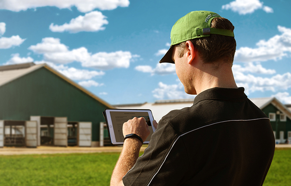 Un agriculteur équipé d’une tablette se tient devant sa ferme et s’inscrit à la newsletter