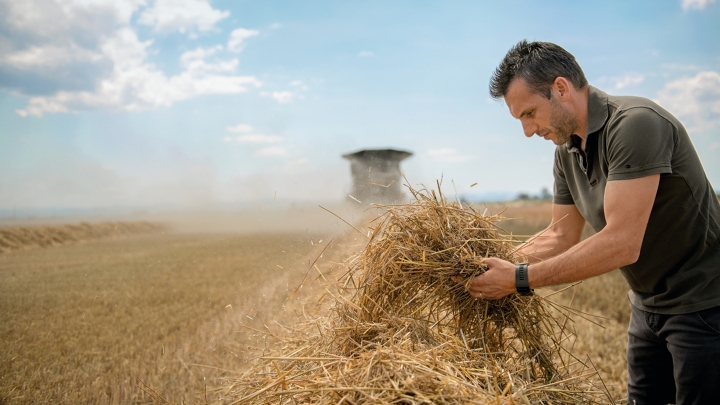 Un homme vérifie la paille dans le champ devant la Fendt IDEAL.