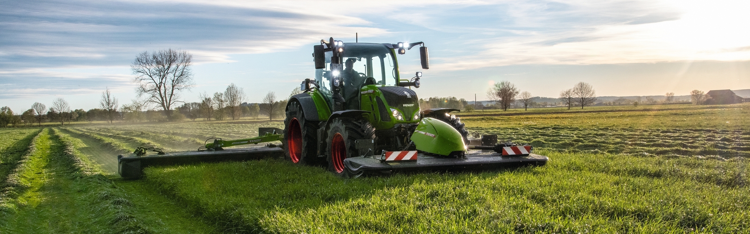 Un tracteur Fendt avec sa faucheuse triple Slicer pendant la récolte de l'herbe
