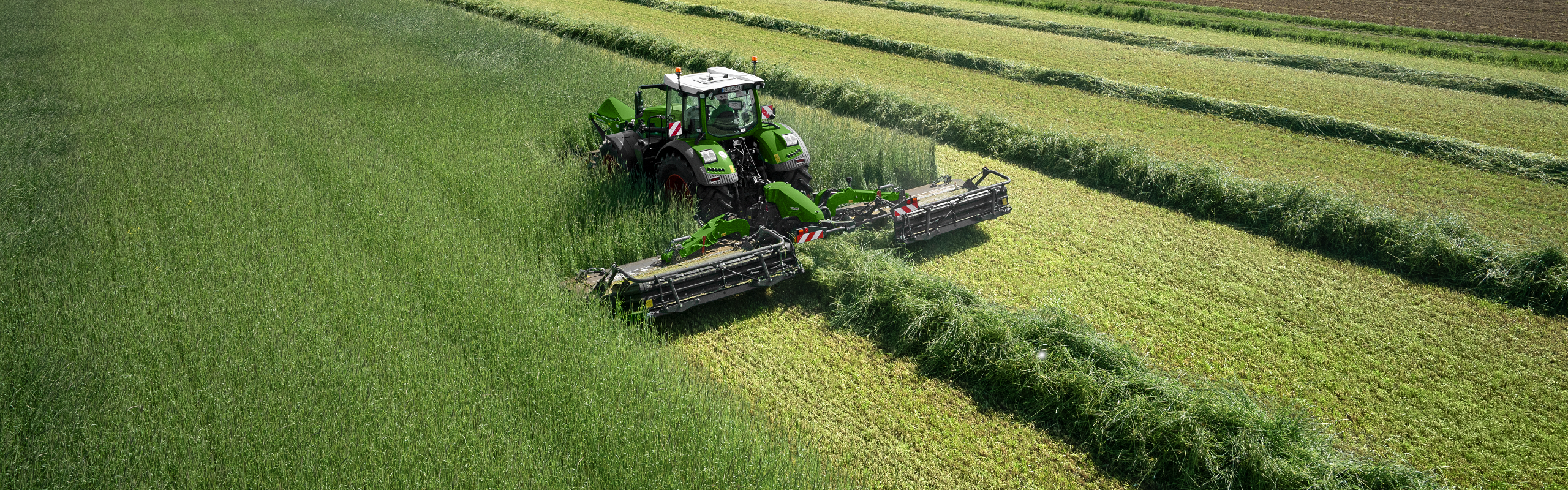 Un tracteur Fendt Vario lors de la récolte du fourrage vert dans l'herbe haute avec une combinaison de fauche Fendt Slicer.
