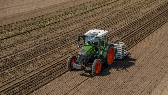 Un Fendt e100 Vario roule dans un champ et travaille le sol.
