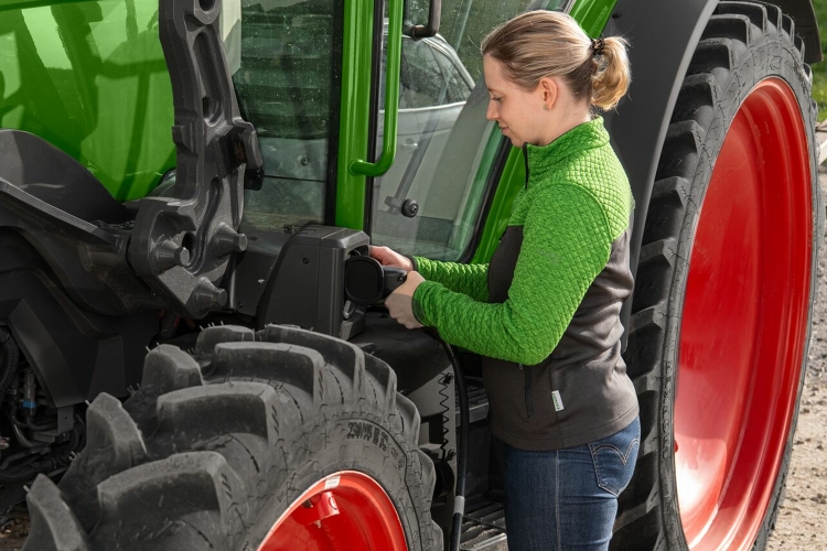 Une agricultrice branche son tracteur électrique pour le recharger.