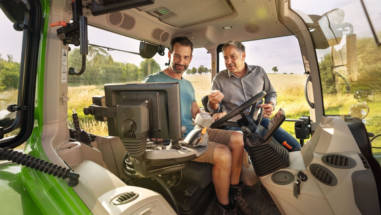 Un concessionnaire Fendt dans la cabine d'un modèle de tracteur vert de démonstration Fendt chez un client agriculteur sur le terrain