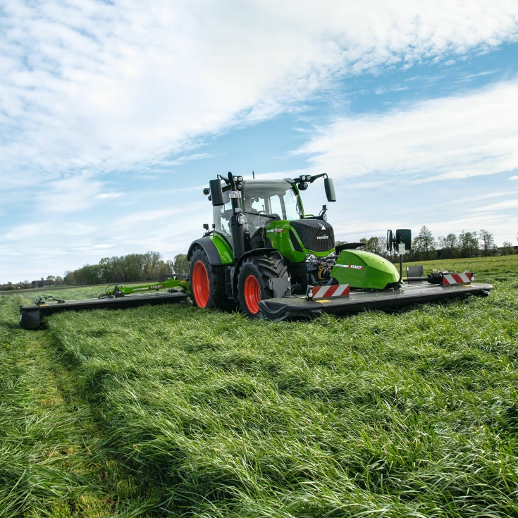 Le tracteur Fendt se déplace dans le champ avec des faucheuses frontale et arrière Fendt Slicer