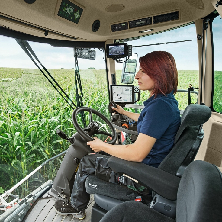 Une agricultrice est assise dans son Fendt Katana et dirige la machine à travers un champ de maïs.