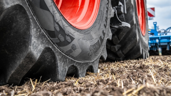 Gros plan sur des pneus Fendt à jantes rouges dans un champ