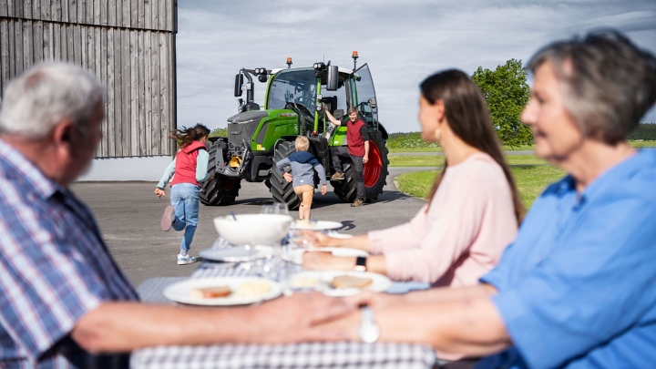 La famille entière réunie autour de la table dressée à la ferme se réjouit de l'arrivée de ses deux derniers membres : l'agriculteur et le Fendt 300 Vario.