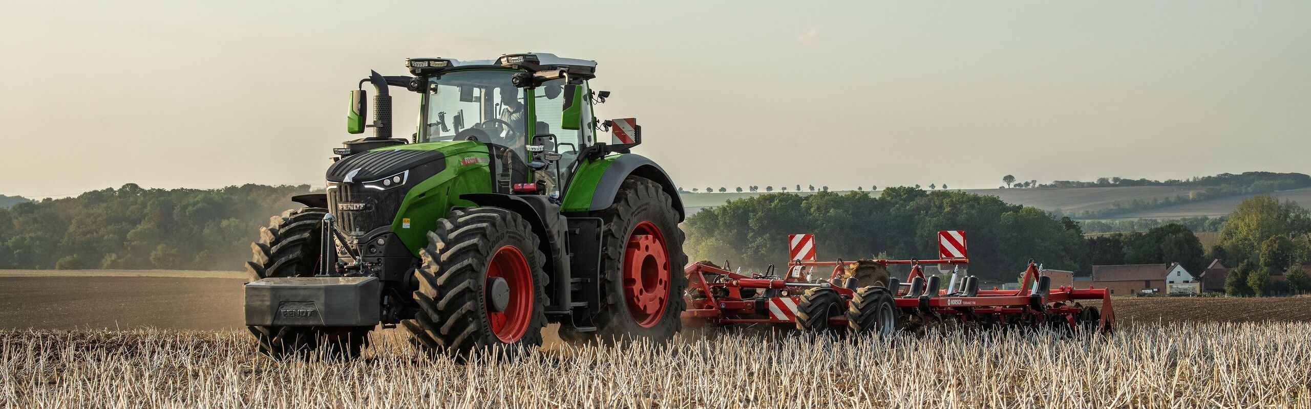 Un Fendt 1000 Vario Gen4 vert traverse un champ de chaumes pour travailler le sol