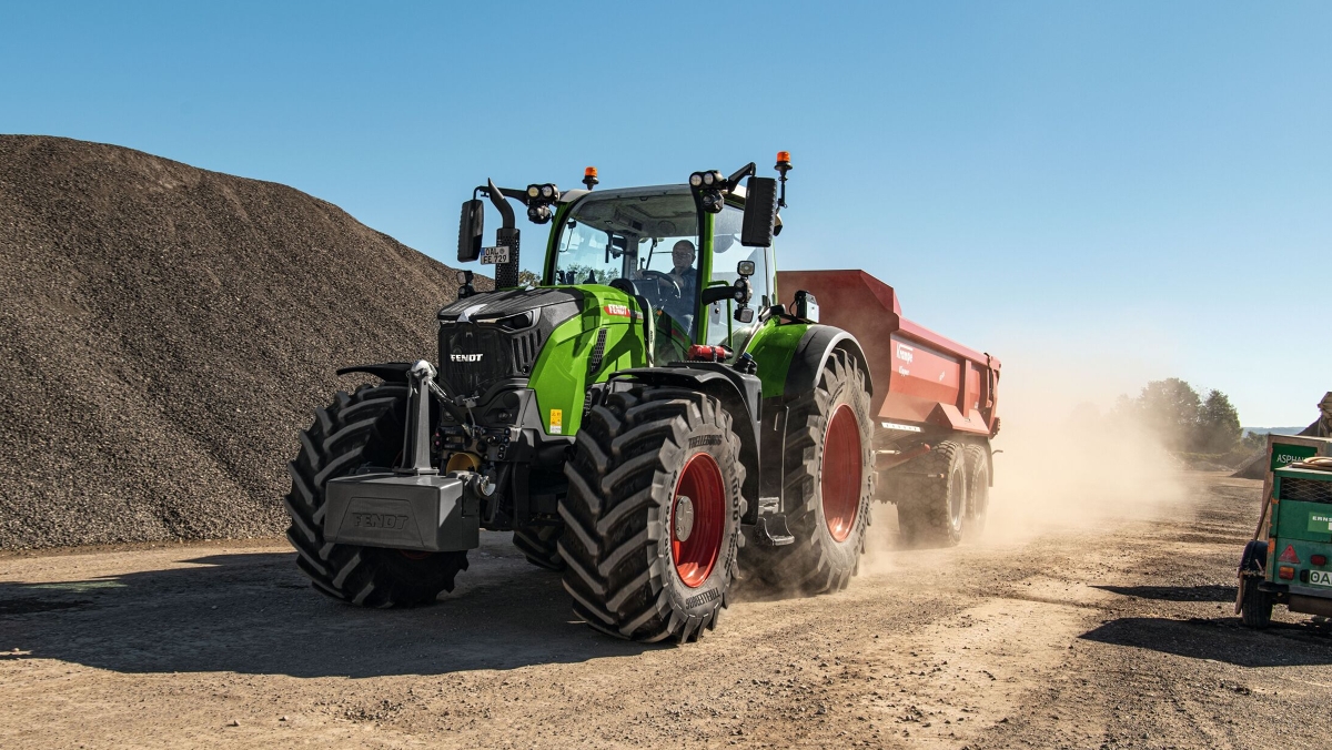 Fendt 700 Vario Gen7 Transport Un agriculteur roule avec un Fendt 700 Vario Gen7 et une benne Krampe rouge. La faible consommation