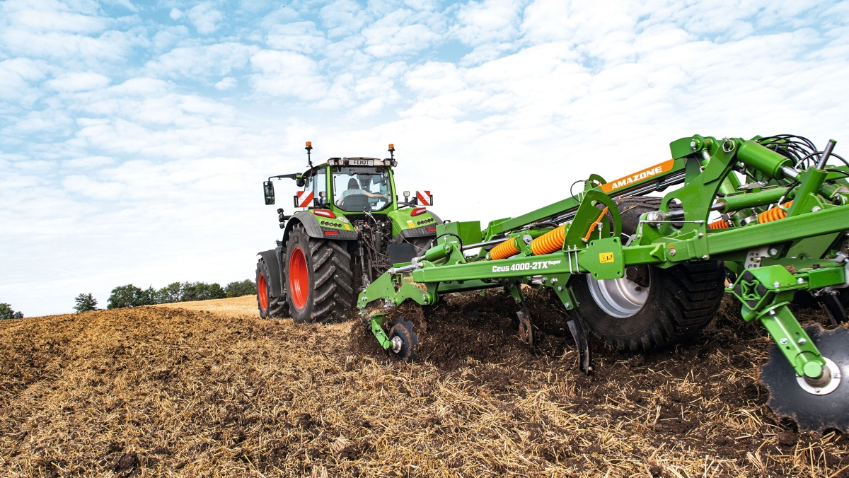 Fendt 700 Vario Gen7 en action dans les champs Une agricultrice conduit un Fendt 700 Vario Gen7 et un cultivateur Amazone dans un champ.