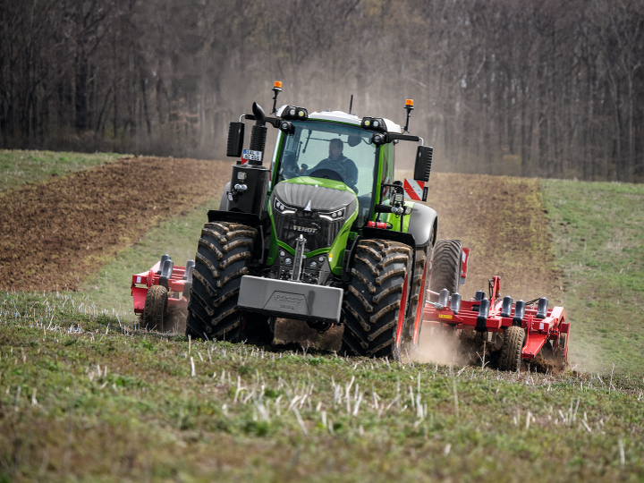 Egy Fendt traktor halad a mezőn és port kavar fel.