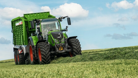 Fendt 700 Vario Gen6 Fendt Tigo rakodókocsival Egy gazda egy Fendt 700 Vario Gen6-tal és egy Fendt Tigo rakodókocsival halad a mezőn és füvet rakodik fel.
