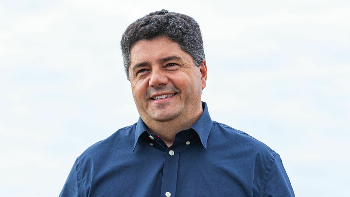 Lucio Basso portréja sötétkék ingben, halvány fehér-kék égbolttal a háttérben