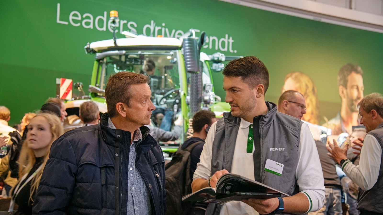A Fendt egyik munkatársa a kiállítás egy látogatójával beszélget az Agritechnica 2023 kiállításon