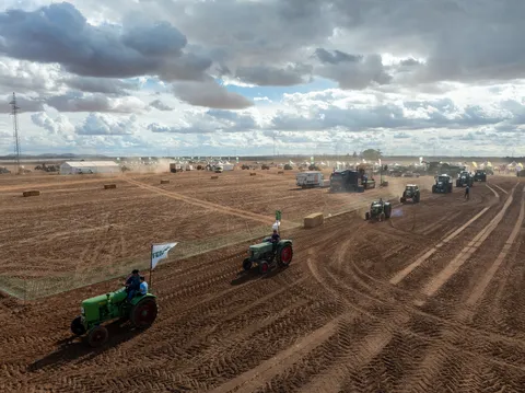 A parade of Fendt tractors drives by with flags