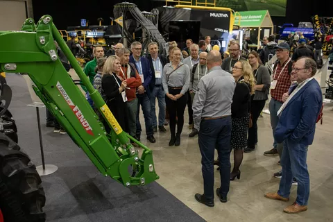 A group of visitors stands in front of the front loader of the Fendt 600 Vario at Maatalous Konemessut 2024 in Finland and listens to a speaker