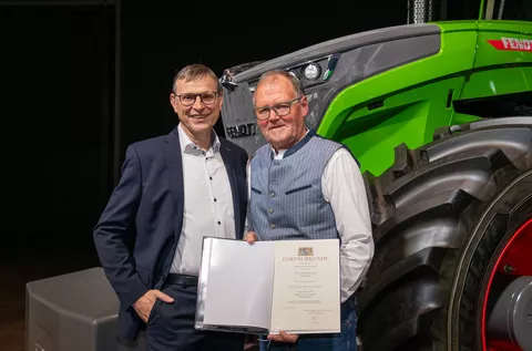 Walter Wagner and Michael Horn in front of a Fendt tractor with Michael Horn's certificate of honour