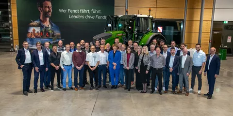 Group photo of Fendt employees celebrating 25 years of service with Fendt management in front of a Fendt tractor