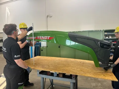 3 men (apprentices), 2 holding the bonnet (left and right), one measuring the height with a folding rule.