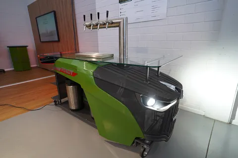 Fendt dispensing station (diagonally from the front) with Fendt logo, a glass shelf and front and rear lights switched on.