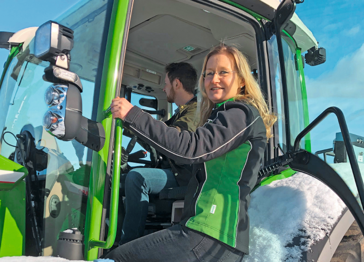 Christine Hain looks out of the Fendt tractor into the camera.