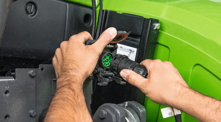 A hand inserts a plug into the ISOBUS socket.