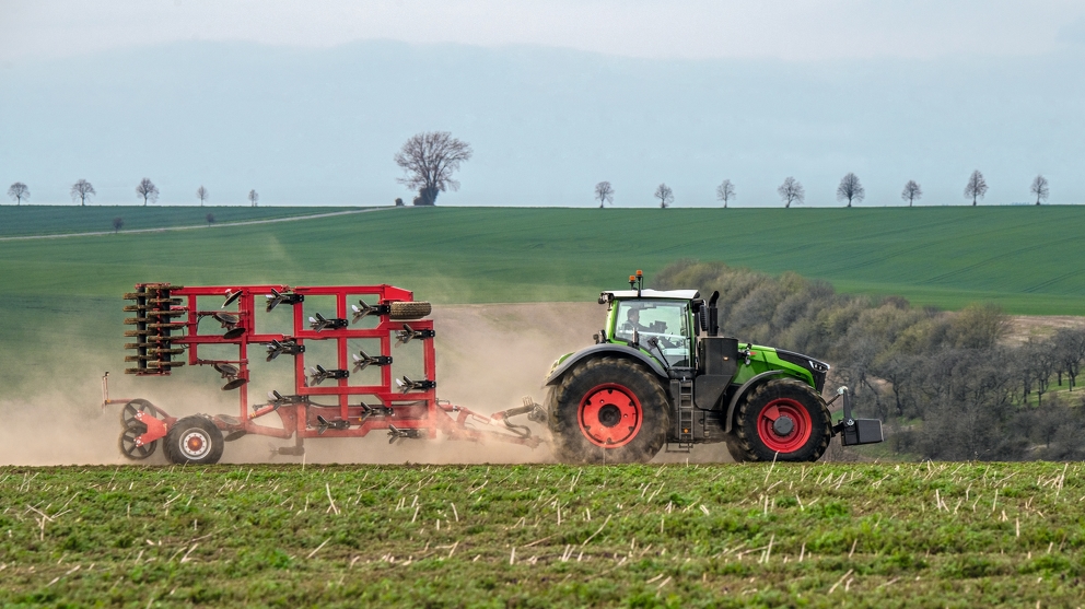 Side view of the Fendt 1000 Vario with folded attachment in a field