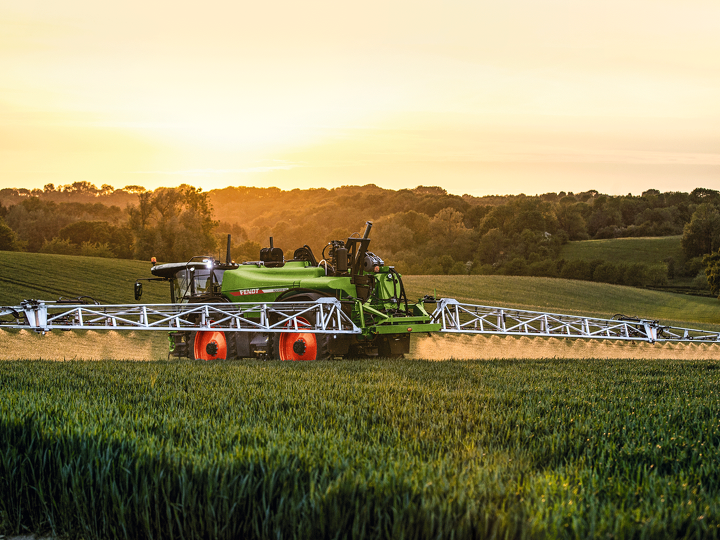 Fendt Rogator 600 crop protection sprayer in a grain field at sunset.