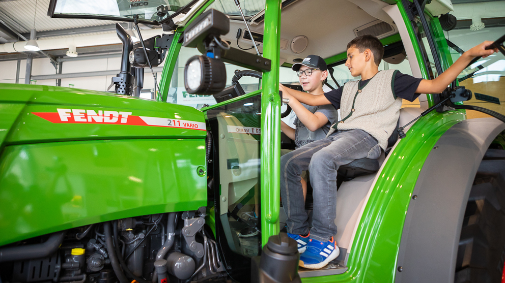 Two children are sitting in the Fendt 200 Vario.