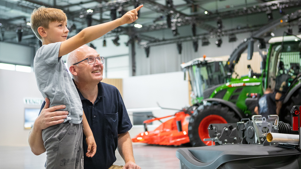 An elderly man and his grandson inspect the products in the Fendt Global Forum.