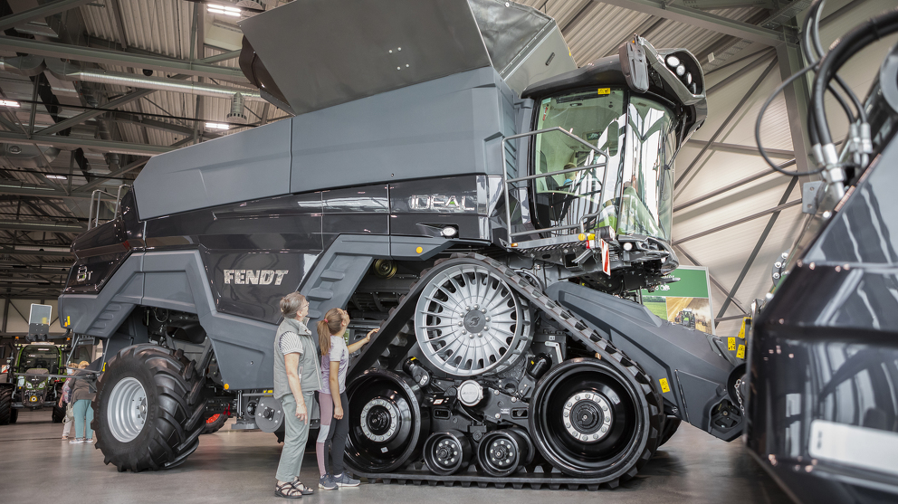 Visitors are standing in front of the Fendt IDEAL combine harvester at the Fendt Forum.