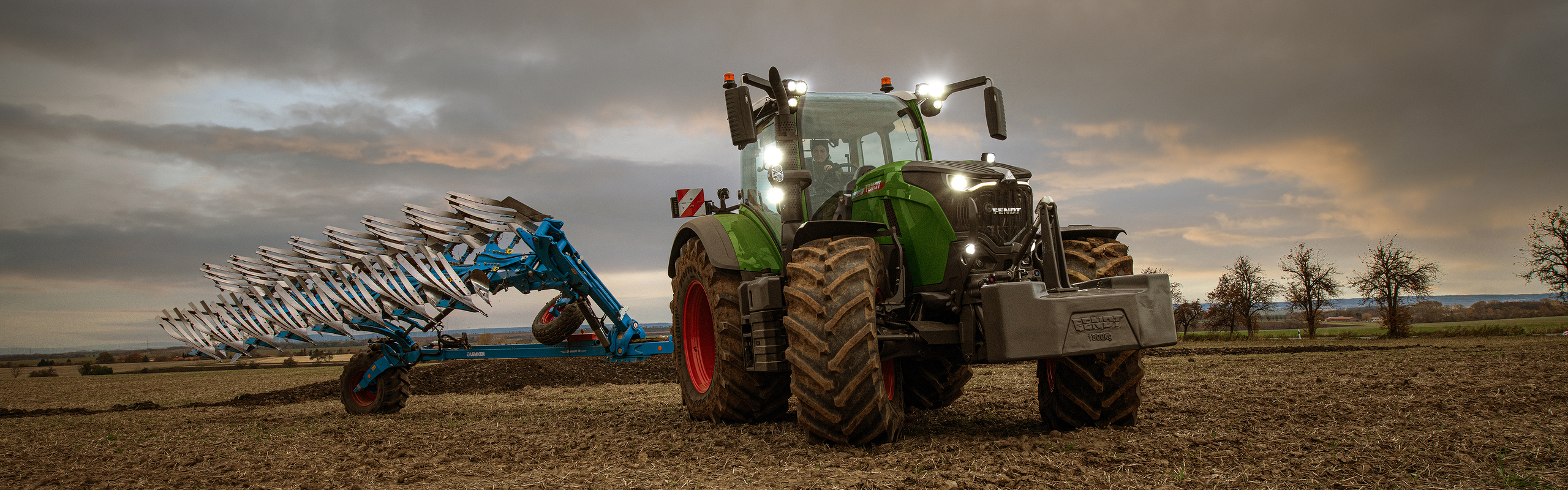 A female farmer drives the Fendt 700 Vario Gen7 in the field at twilight.